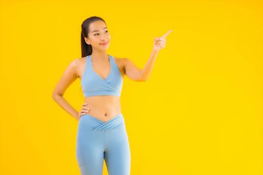 Sarı izole edilmiş arka planda spor giysili güzel Asyalı kadın portresi egzersize hazır.