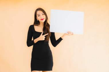 Güzel bir Asyalı kadın portresi boş beyaz ilan panosunu izole edilmiş arka planda gösteriyor.