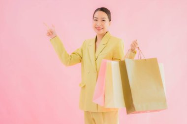 Renkli arka planda alışveriş çantası taşıyan güzel Asyalı iş kadını portresi.