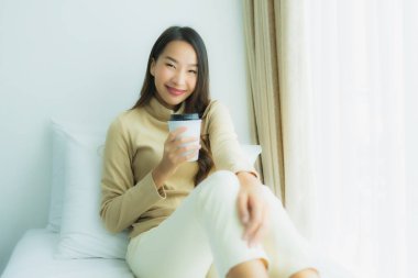 Yatak odasının iç tarafında, kahve fincanı olan Asyalı genç bir kadın.