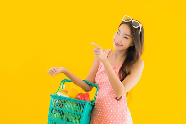 노란색외진 배경에 슈퍼마켓에서 바구니에 식료품을 아름다운 아시아 여자의 — 스톡 사진