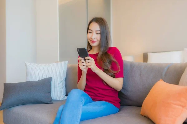 在卧室内部的生活区 形象漂亮的年轻亚洲女人在沙发上使用智能手机 — 图库照片