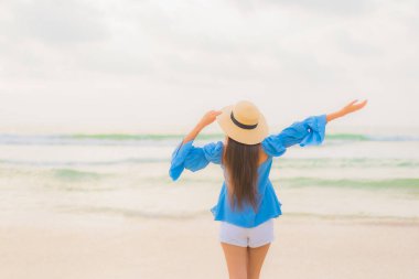 Güzel bir Asyalı kadın portresi. Gün batımında deniz kıyısında rahatça gülümse.