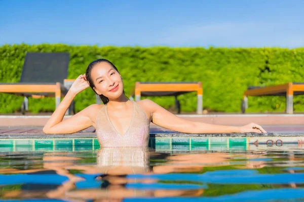 美丽的年轻亚洲女人在酒店度假胜地的室外游泳池边悠闲自在地笑着 — 图库照片
