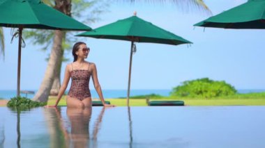 Güzel Asyalı bir kadının oteldeki havuzda dinlenirken çekilmiş görüntüleri.