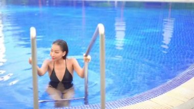 Güzel Asyalı bir kadının oteldeki havuzda dinlenirken çekilmiş görüntüleri.