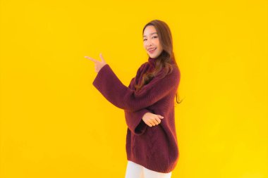 Güzel Asyalı kadın gülümsüyor. Sarı izole edilmiş arka planda başka bir eylemde mutlu.