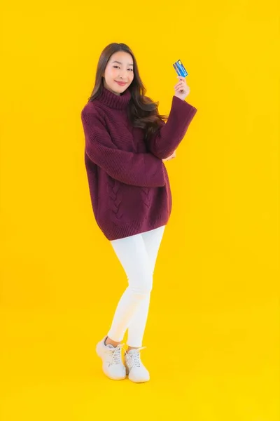 亚洲年轻貌美的女性形象 带着信用卡在黄色隔离背景下网上购物 — 图库照片