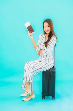 Güzel Asyalı bir kadının portresi. Bavul pasaportu ve biniş kartı mavi arka planda seyahat için hazır.
