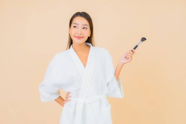 Renkli arka planda makyaj fırçası olan güzel bir Asyalı kadın portresi.