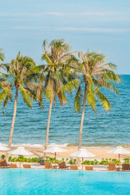Şemsiye ve iskemle, oteldeki deniz kıyısı ve hindistan cevizi palmiyesi olan havuzda yüzüyor.