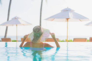 Güzel bir Asyalı kadın portresi. Tatil gezisinde deniz manzaralı açık havuz etrafında rahatça yüzebiliyor.