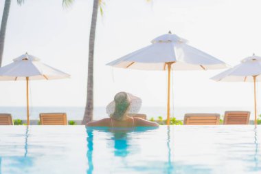 Güzel bir Asyalı kadın portresi. Tatil gezisinde deniz manzaralı açık havuz etrafında rahatça yüzebiliyor.