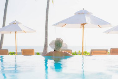 Güzel bir Asyalı kadın portresi. Tatil gezisinde deniz manzaralı açık havuz etrafında rahatça yüzebiliyor.