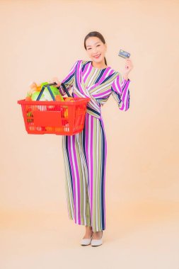 Marketten aldığı alışveriş sepetiyle güzel bir Asyalı kadının portresi. Renkli, izole arka plan.