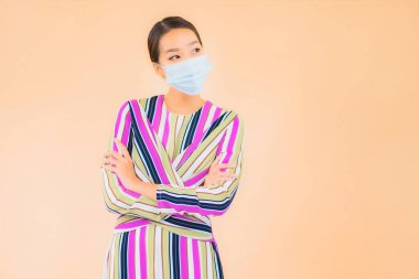 Güzel Asyalı bir kadının portresi Corona virüsünü korumak için maske takıyor ya da renkli arka planda covid19 giyiyor.