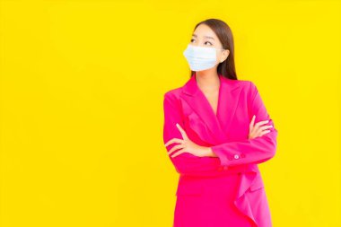 Güzel bir Asyalı kadın koronavirüsü korumak için maske takıyor ya da sarı arka planda 19 numara giyiyor.
