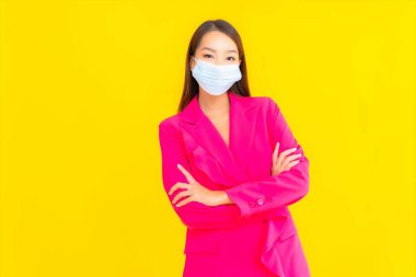 Güzel bir Asyalı kadın koronavirüsü korumak için maske takıyor ya da sarı arka planda 19 numara giyiyor.