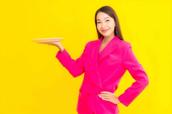 黄色の色のプレートや皿を持つ肖像画の美しい若いアジアの女性孤立した背景 — ストック写真