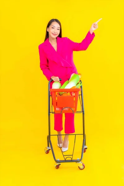 色の背景にスーパーマーケットからバスケットやカートや食料品と肖像画の美しい若いアジアの女性 — ストック写真