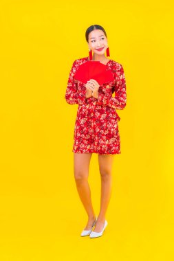Sarı arka planda kırmızı zarfları olan güzel Asyalı kadın portresi.