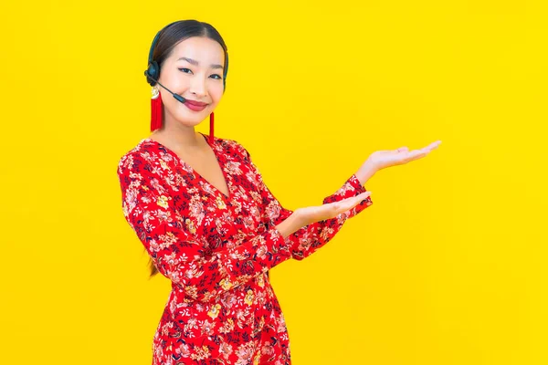 亚洲年轻貌美的女性形象 带着耳机 为客户提供黄色背景的呼叫中心护理服务 — 图库照片