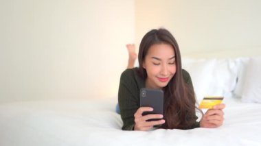 Evde akıllı telefon kullanan Asyalı güzel bir kadının görüntüleri.