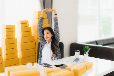 Güzel Asyalı iş kadını portresi evden bilgisayarlı cep telefonuyla karton kutuyla çevrimiçi alışveriş için hazır bekliyor.