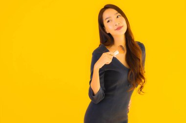 Sarı izole arkaplanda makyaj fırçası olan güzel bir Asyalı kadın portresi.