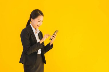 Portre güzel genç Asyalı kadın akıllı cep telefonu ve kahve fincanı ile izole edilmiş sarı arka planda