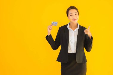 Sarı izole edilmiş arka planda kredi kartı olan güzel, genç Asyalı kadın portresi.