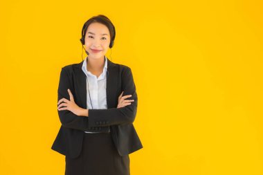 Portre güzel genç Asyalı kadın kulaklık ya da çağrı merkezi için kulaklık ya da tele pazarlama sarı izole arka planda.