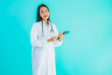 Steteskoplu ve akıllı tabletli güzel Asyalı doktor kadının portresi mavi arka planda hastane ve klinikte kullanılacak.