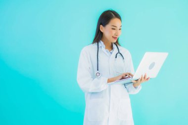 Bilgisayarlı güzel Asyalı doktor kadın portresi klinikte ya da mavi izole arka planda hastanede kullanılacak.