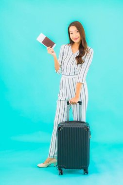 Güzel Asyalı bir kadının portresi. Bavul pasaportu ve biniş kartı mavi arka planda seyahat için hazır.