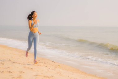 Portre sporu genç Asyalı kadın egzersiz hazırlıyor ya da sağlık için okyanusta koşuyor.