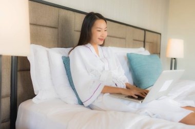 Genç Asyalı güzel kadınların portresi. Yatak odasındaki yatak odasında bilgisayar ya da dizüstü bilgisayar kullanıyorlar.