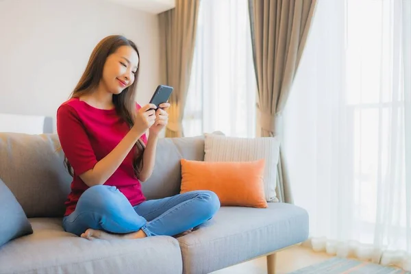 在卧室内部的生活区 形象漂亮的年轻亚洲女人在沙发上使用智能手机 — 图库照片