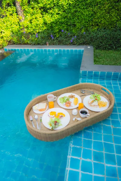 Floating breakfast around outdoor swimming pool in hotel resort