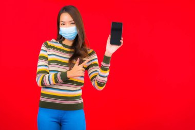 Kovid19 'u korumak için telefon maskeli güzel Asyalı kadın portresi.