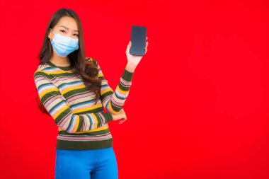 Kovid19 'u korumak için telefon maskeli güzel Asyalı kadın portresi.