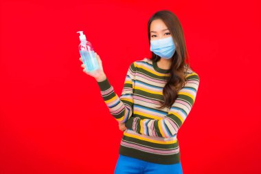 Kırmızı izole edilmiş arka planda alkol jeli güzel Asyalı kadın portresi.