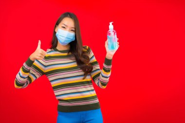 Kırmızı izole edilmiş arka planda alkol jeli güzel Asyalı kadın portresi.