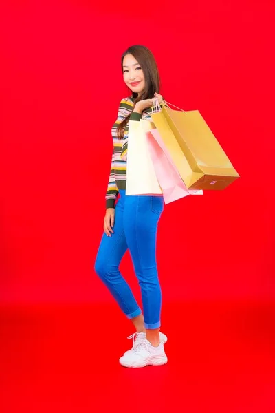 色彩艳丽的年轻亚洲女人 背景是红色的购物袋和信用卡 — 图库照片