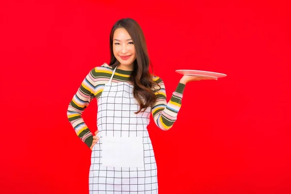 肖像美しい若いアジアの女性は赤い背景に空の料理を見る — ストック写真