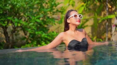 Havuzda dinlenen güzel bir Asyalı genç kadının görüntüleri.