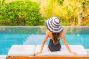 Güzel bir Asyalı kadının portresi tatil için yüzme havuzunda rahatlıyor.