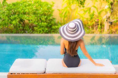 Güzel bir Asyalı kadının portresi tatil için yüzme havuzunda rahatlıyor.