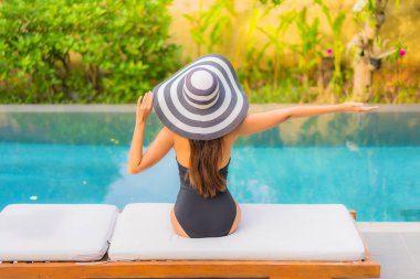 Güzel bir Asyalı kadının portresi tatil için yüzme havuzunda rahatlıyor.