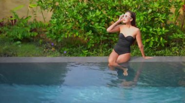 Havuzda dinlenen güzel bir Asyalı genç kadının görüntüleri.